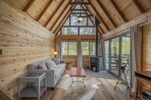 A cozy cabin interior with a wooden interior, a sofa, a table, and a fireplace.