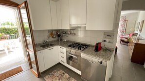Ett kompakt kök med vita skåp, en gasspis, en diskmaskin från Bosch och ett litet handfat.
