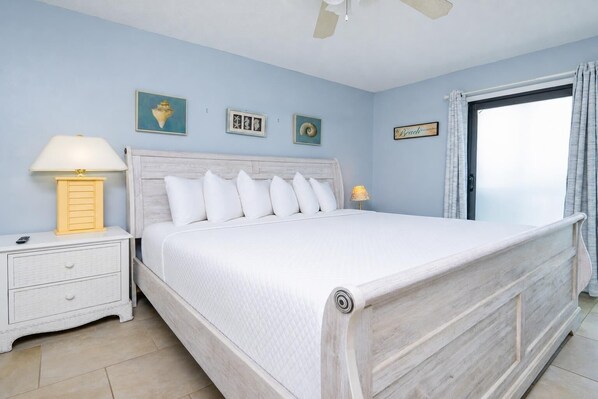 A bedroom with a bed, nightstand, lamp, and artwork on the wall.
