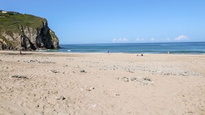 A beach with rocky terrain and a cliff. - 16 Seaspray (Truro)