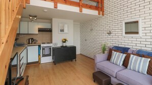 A modern kitchen with white cabinets, a black countertop, and a wooden staircase. - 16 Seaspray (Truro)