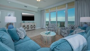 A spacious living room with a large sofa set, a coffee table, and a flat-screen TV.