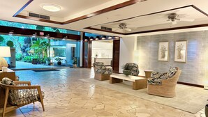 A lobby with a stone floor, wicker furniture, a ceiling fan, and framed artwork on the walls.