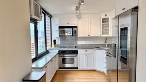 A modern kitchen with white cabinets, a stainless steel refrigerator, a built-in oven, and a microwave.
