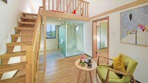 A modern interior with a wooden staircase, a round table with a cup and saucer, and a green chair. - Wuzhen Dream Hotel (Jiaxing)