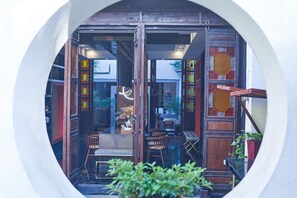 A traditional wooden building with a circular window, wooden furniture, and potted plants.