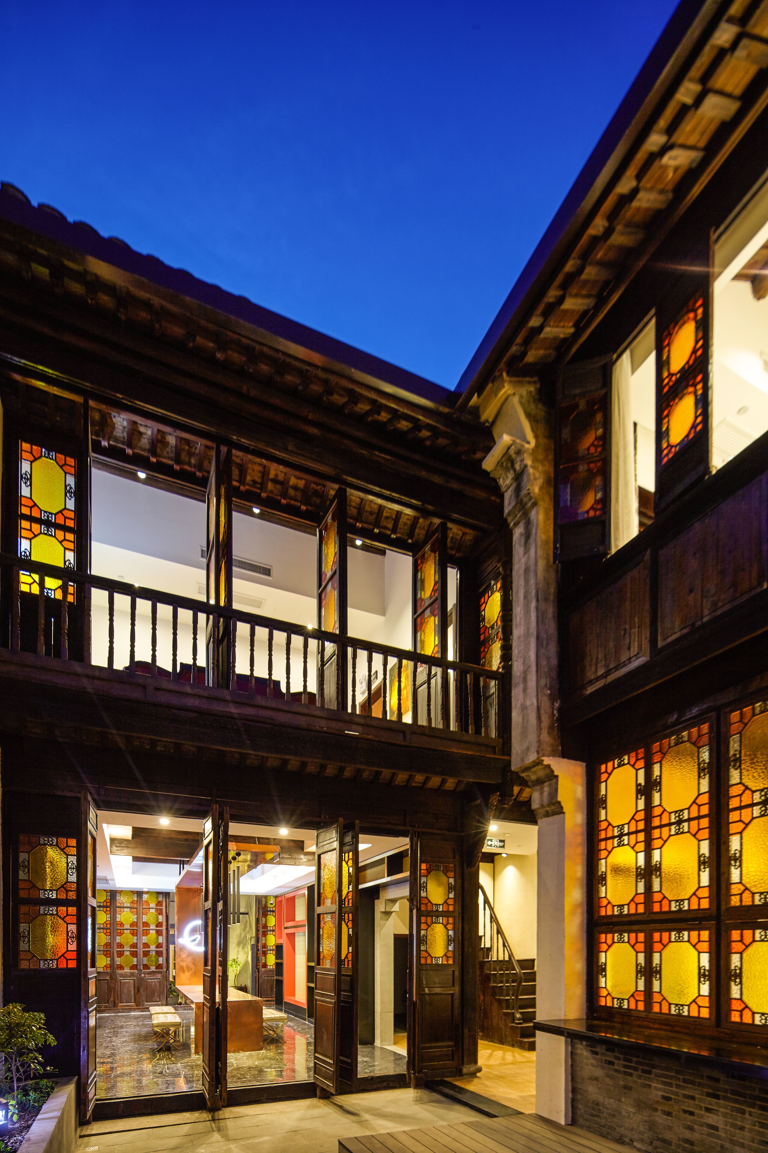 A traditional building with a balcony, large windows with stained glass, and a staircase leading to an upper level.