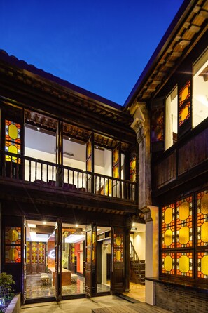 A traditional building with a balcony, large windows with stained glass, and a staircase leading to an upper level.