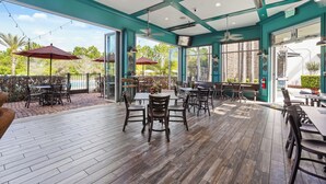Un espace extérieur aménagé en terrasse, avec un sol en bois, des tables, des chaises et des parasols.