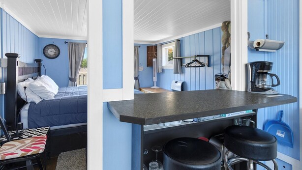 A compact room with a bed, a small table, a bar area with stools, and a kitchen counter. - Romantic, Walk to town and beach, Private (ArchView) (Long Beach)