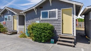 A row of mobile homes with a front porch, a small garden, and a sign indicating a parking area. - Romantic, Walk to town and beach, Private (ArchView) (Long Beach)