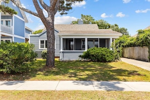 A two-story house with a front porch, a small garage, and a well-maintained lawn.