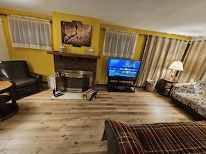 Ein Wohnzimmer mit Kamin, Fernseher, Sofa und Couchtisch.