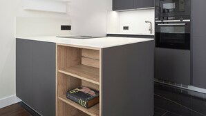 A modern kitchen with grey cabinets, a white countertop, and built-in appliances including a microwave and oven. - Elkano by FeelFree Rentals (Donostia)