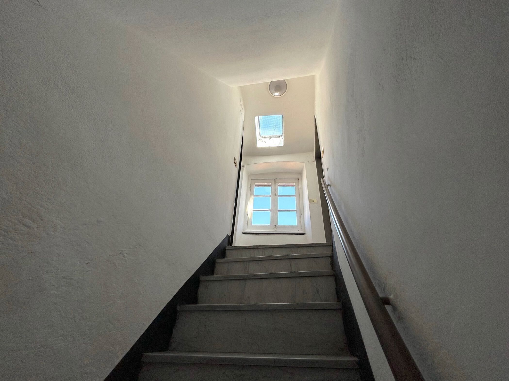 Un escalier étroit avec une fenêtre en haut.