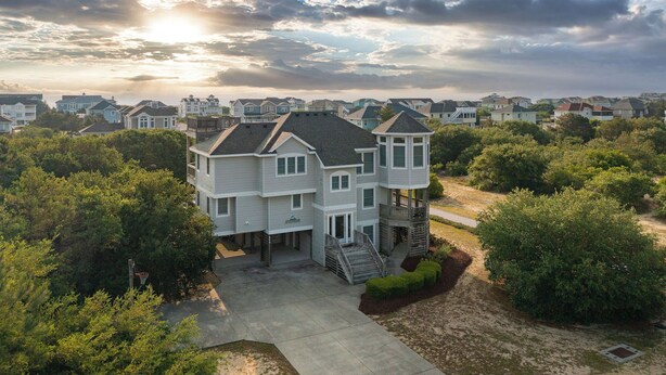 A multi-story residential building with a central entrance, a covered porch, and a staircase leading to a second-floor balcony. - Near the Beach! Saltwater Pool, Hot Tub, Great Neighborhood, C0949 (Corolla)