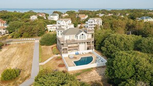 A large house with a swimming pool, surrounded by trees and other houses. - Near the Beach! Saltwater Pool, Hot Tub, Great Neighborhood, C0949 (Corolla)