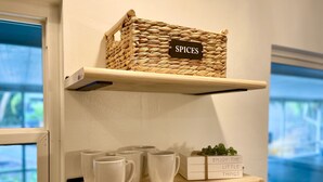 Una repisa de cocina con una cesta tejida que dice "ESPECIAS" y una caja con el texto "DISFRUTA LAS PEQUEÑAS COSAS".