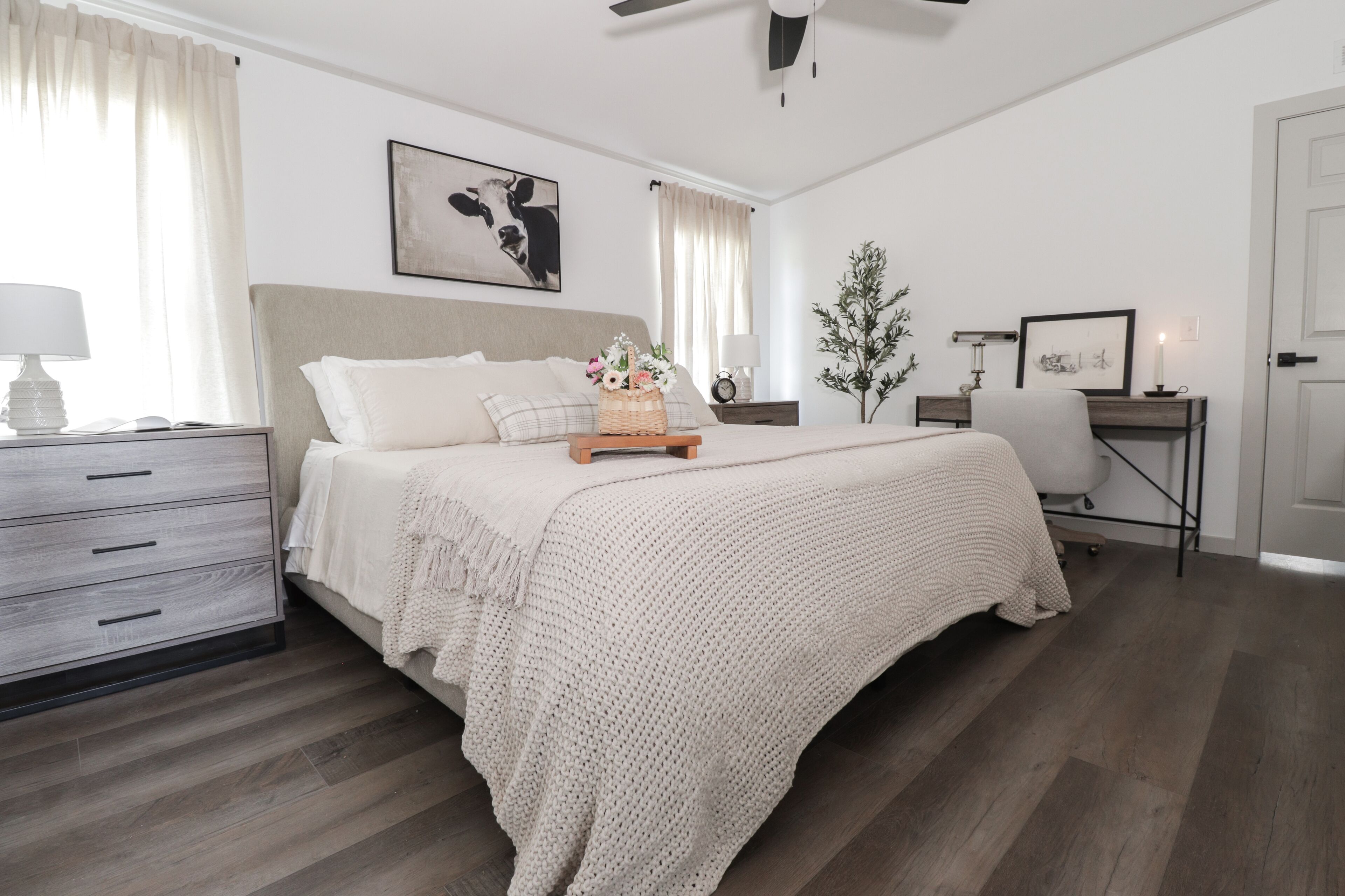 A bedroom with a bed, bedside table, lamp, and a wall-mounted clock.
