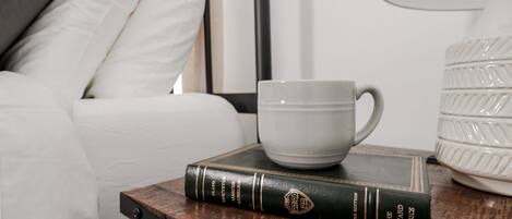 A wooden nightstand with a book titled "The Harvard Classics" and a white mug.