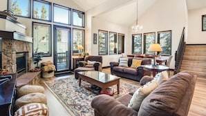 A spacious living room with a fireplace, large windows, and a cozy seating area. - Breckenridge White Wolf Townhome 4 Bedroom (Breckenridge)