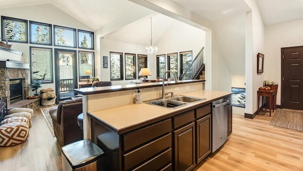 A modern kitchen with a large island, built-in appliances, and a view of the outdoors through large windows. - Breckenridge White Wolf Townhome 4 Bedroom (Breckenridge)