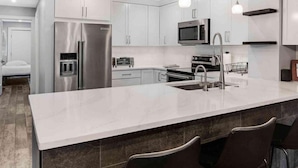 A modern kitchen with stainless steel appliances, a large island, and bar stools.