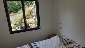 Une chambre à coucher avec un lit, une fenêtre, une table de chevet et une prise électrique au mur.