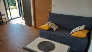 Un salon moderne avec un canapé gris, deux coussins jaunes et une petite table sur laquelle repose un dessous de verre en fibres tressées.