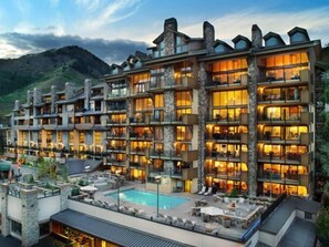 A multi-story hotel with balconies, a swimming pool, and a mountainous backdrop. - Vail Lionshead Village Landmark 1 Bedroom Condo (Vail)