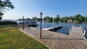 A wooden dock extending into a calm body of water, with a lamp post and benches along the side. - Riverfront Charmer with Character & Entertainment (McHenry)