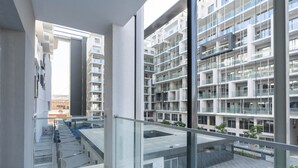 A modern multi-story residential building with balconies and large windows. - Modern Studio in Oasis -607 (Abu Dhabi)