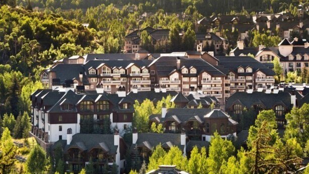 A cluster of chalet-style buildings with multiple stories, surrounded by dense forest.