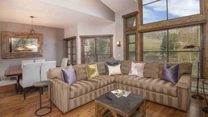 A living room with a sectional sofa, a coffee table, and a dining table with chairs.