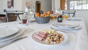 A breakfast setting with plates of food, a basket of croissants, and a glass of juice. - Villa Lemos by HelloVacations (Albufeira)