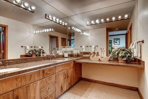 Ein modernes Badezimmer mit zwei Waschbecken, Holzschränken und einem großen Spiegel mit Beleuchtung.