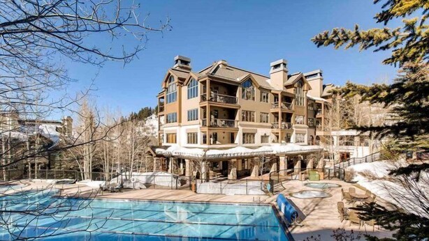 A multi-story hotel with a pool area, including a large pool and a smaller hot tub.