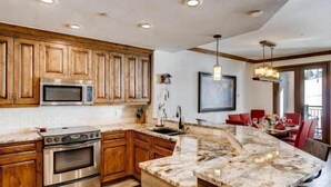 A kitchen with wooden cabinets, stainless steel appliances, and a marble island.