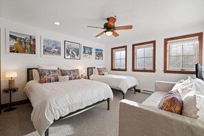 A hotel room with two beds, a ceiling fan, and a large window.
