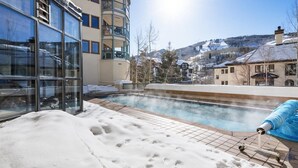 A heated outdoor pool with a view of a snowy mountain landscape and a building with large windows. - Beaver Creek Centennial 2 Bedroom Residence (Avon)