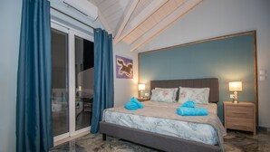 Une chambre à coucher avec un lit, deux tables de chevet, une porte vitrée et un rideau bleu.
