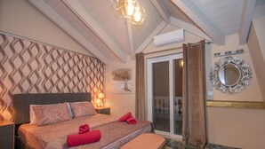 Une chambre à coucher avec un lit, un banc, des œuvres d’art murales et un miroir.