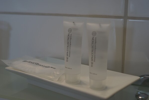 A bathroom with a white sink and two white bottles labeled "The Spa Collection" on a white shelf. - De Bronzen Koets (Nijmegen)