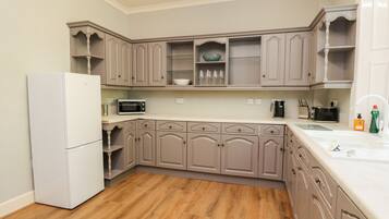 Una cocina con piso de madera, electrodomésticos blancos y gabinetes de colores claros.