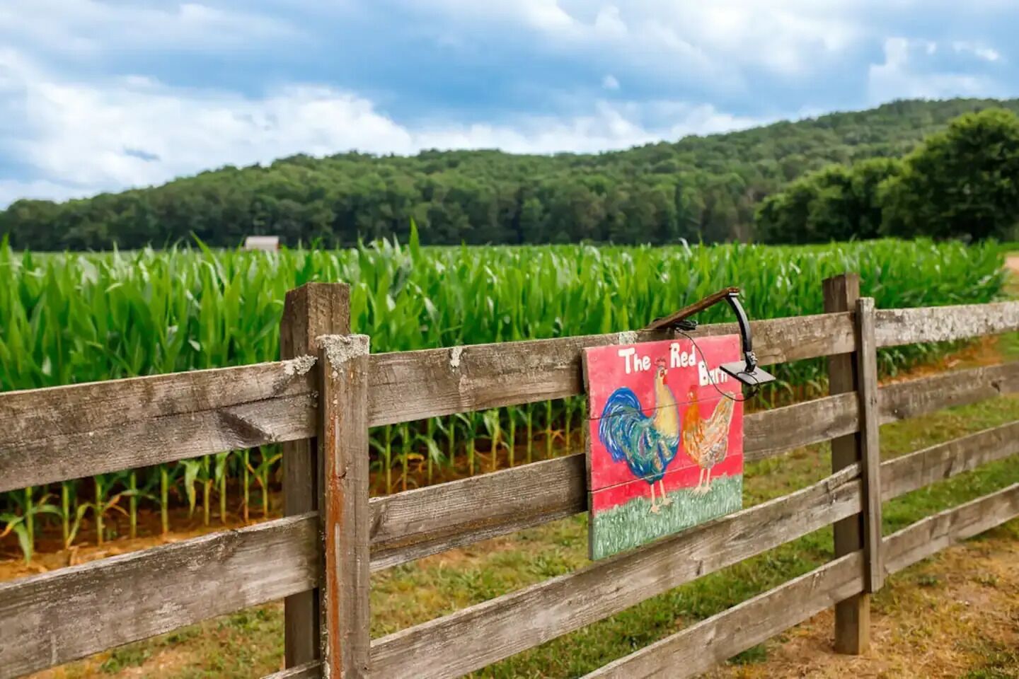 Ein Holzzaun mit einem Schild, auf dem 'The Red Barn' steht.