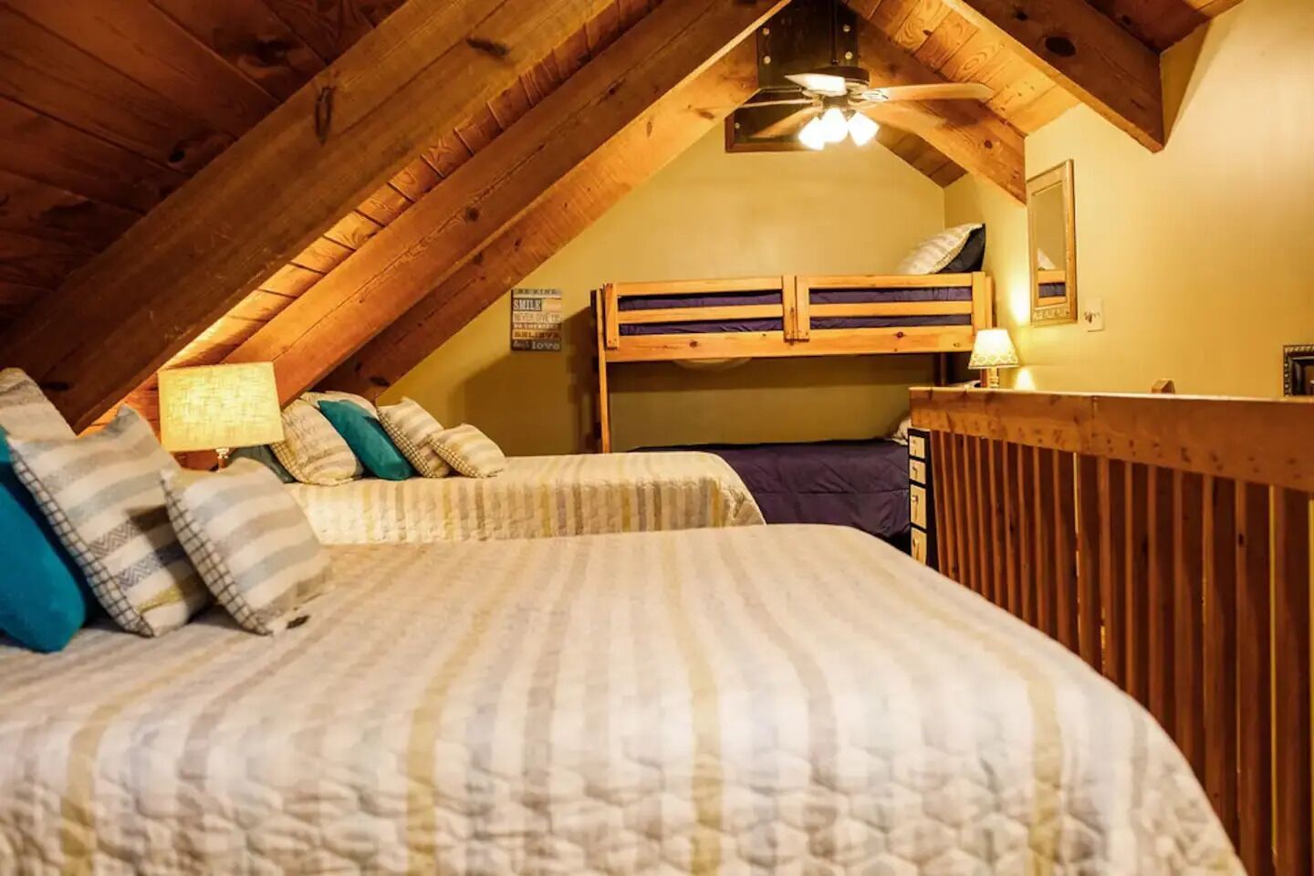 Ein gemütliches Schlafzimmer im Dachgeschoss mit schrägem Dach, Holzbettställen und einer kleinen Arbeitsnische.