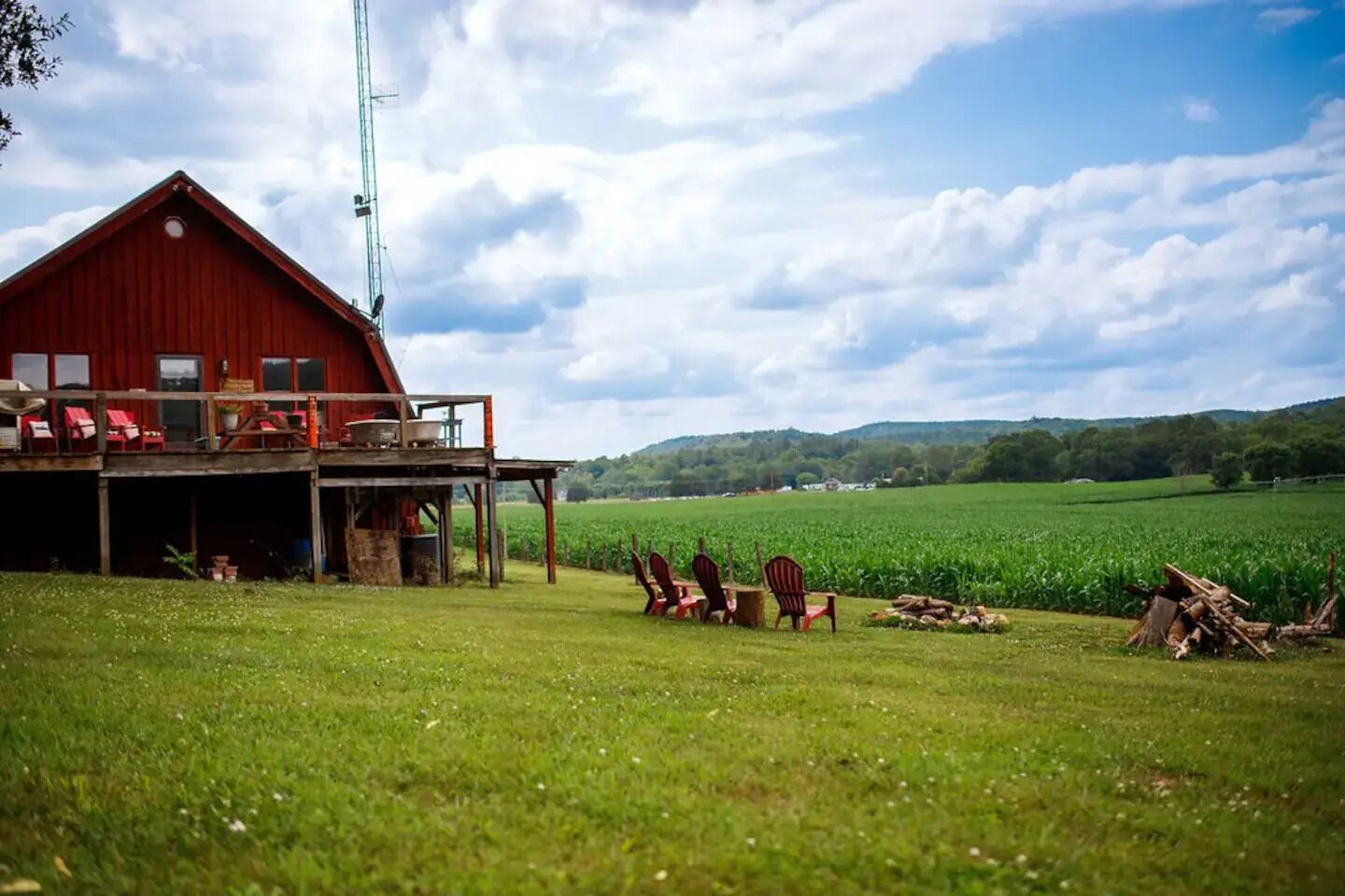 A red barn with a balcony, surrounded by a green field and a clear sky.