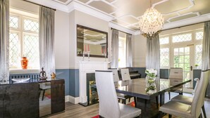 A dining room with a large table, chairs, a chandelier, and a fireplace. - The Hideaway (Hove)