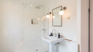 A modern bathroom with a glass-enclosed shower, a pedestal sink, and a mirror with wall-mounted lights. - Feel Discovery Casa do Rio Douro Valley (Baiao)