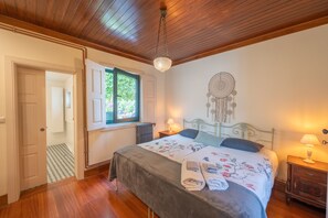 A bedroom with a bed, bedside lamps, a dreamcatcher, and a view of the outdoors. - Feel Discovery Casa do Rio Douro Valley (Baiao)